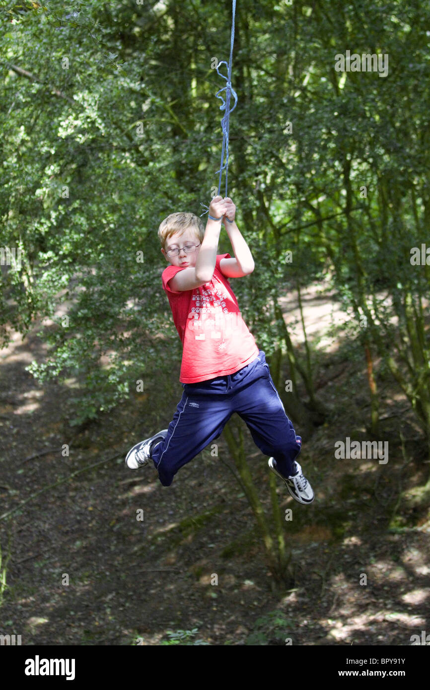 Ein Junge schwingt auf einem Seil schwingen, in einem Landschaftspark Stockfoto