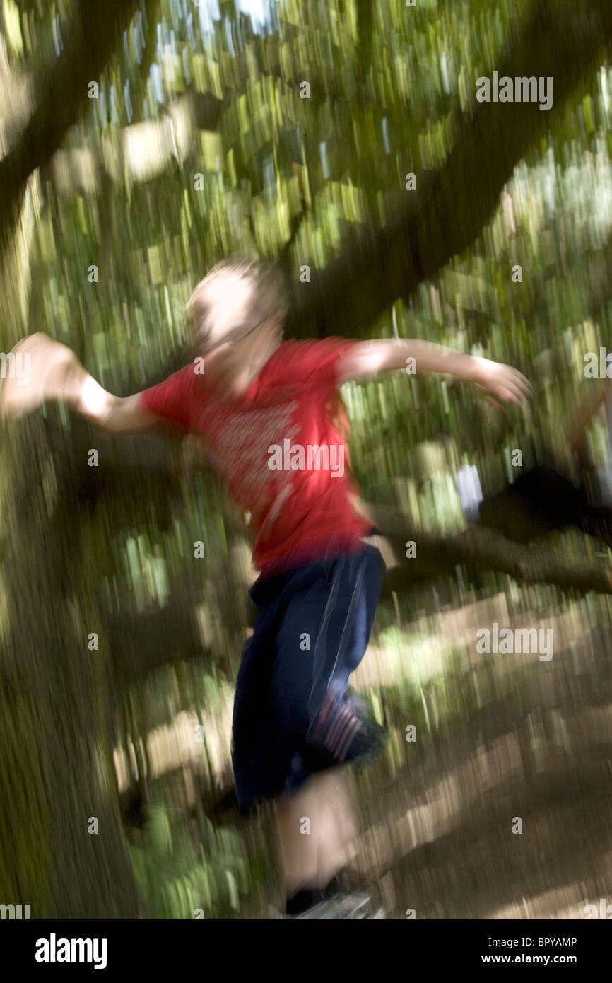 Ein Junge springen oder fallen aus einem Ast Stockfoto