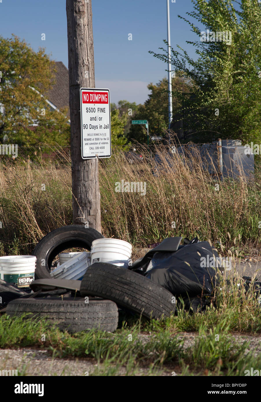 Detroit, Michigan - alte Reifen und anderen Müll wird in einer Gasse neben ein Schild Warnung vor Strafen für illegale Ablagerung abgekippt. Stockfoto