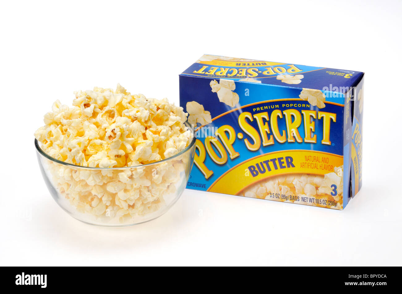 Eine Glasschüssel gefüllt mit Mikrowellen-Popcorn eine Schachtel mit Pop Secret Popcorn dahinter auf weißem Hintergrund, ausgeschnitten. Stockfoto
