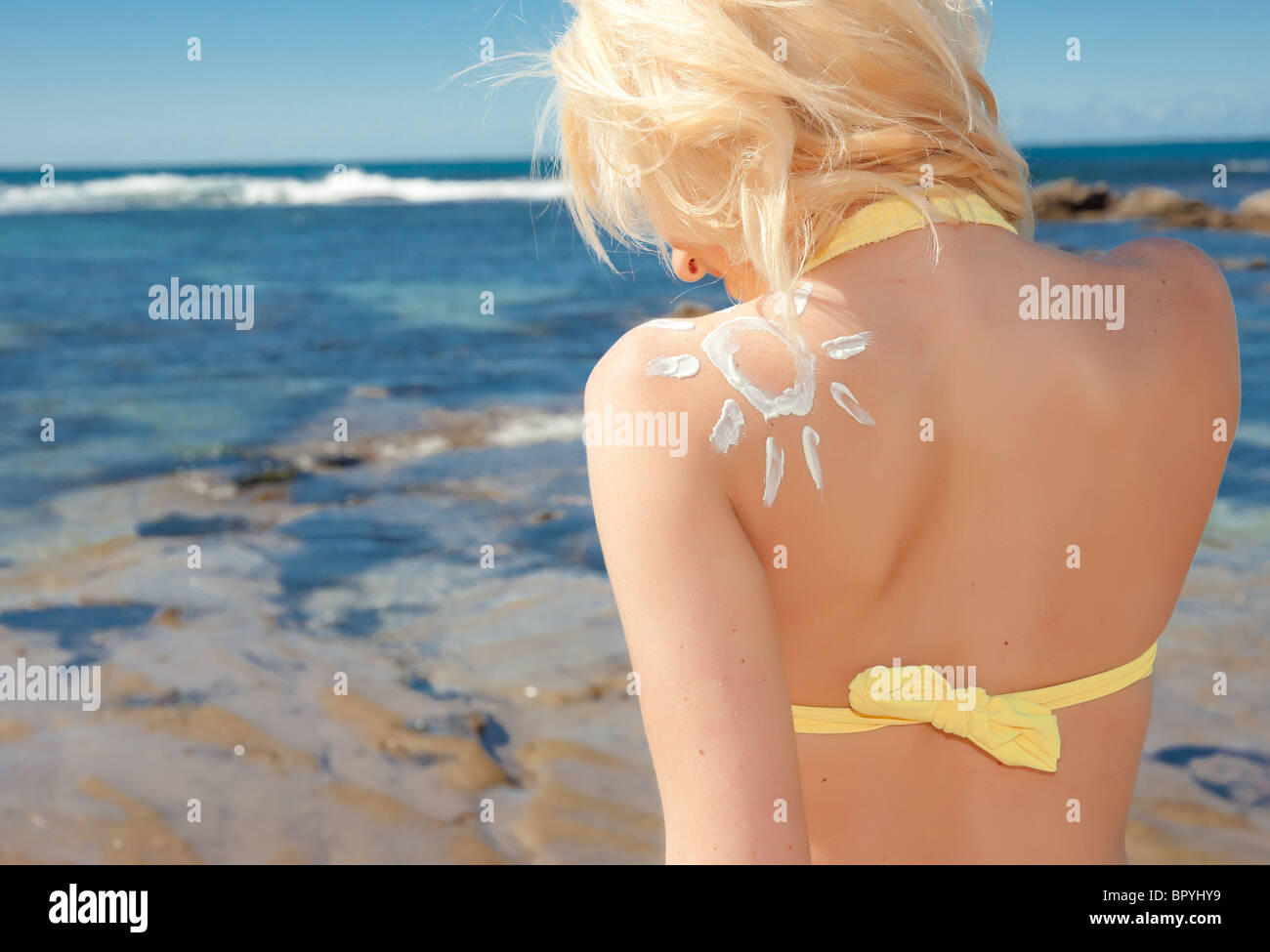 eine schöne junge blonde Frau am Strand mit Sonnenschutz Sonne Stockfoto