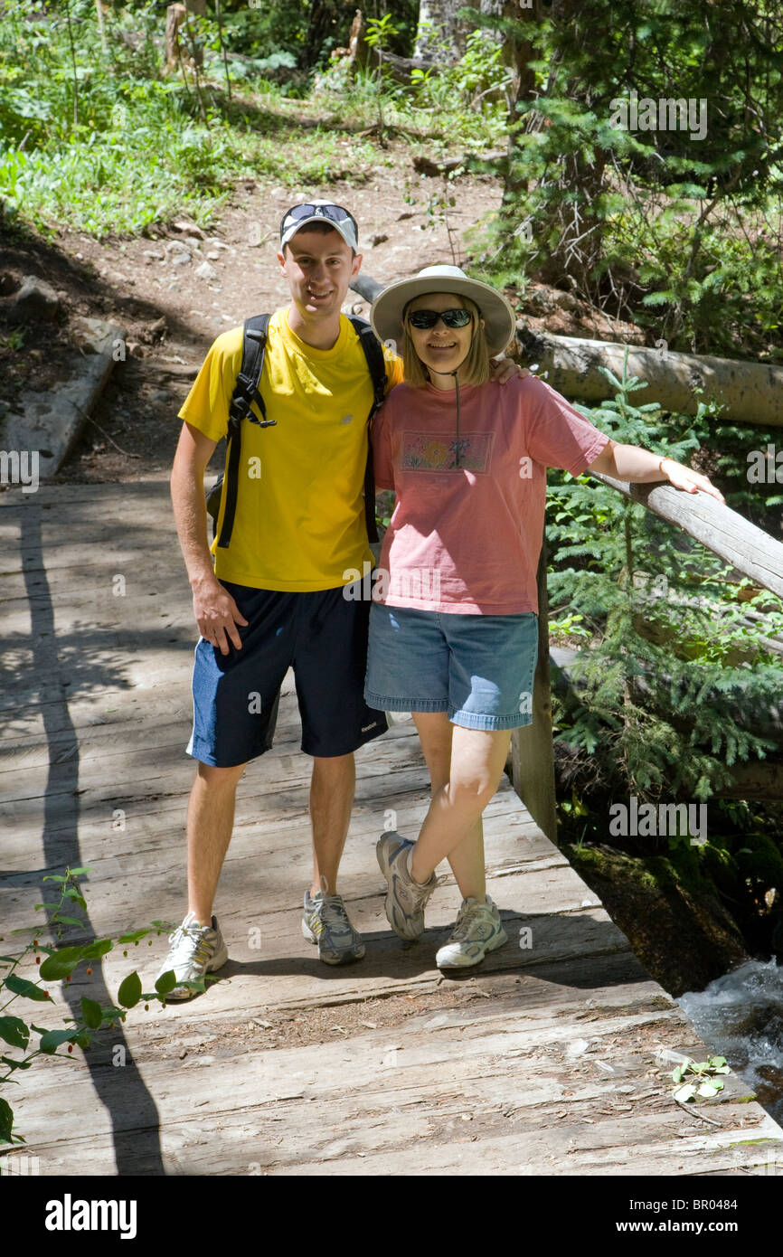 Applying Frau und ihr Sohn Pause von einer Wanderung auf einer Brücke über der Sawatch Range, Chaffee County, South Fooses Creek, Colorado USA Stockfoto