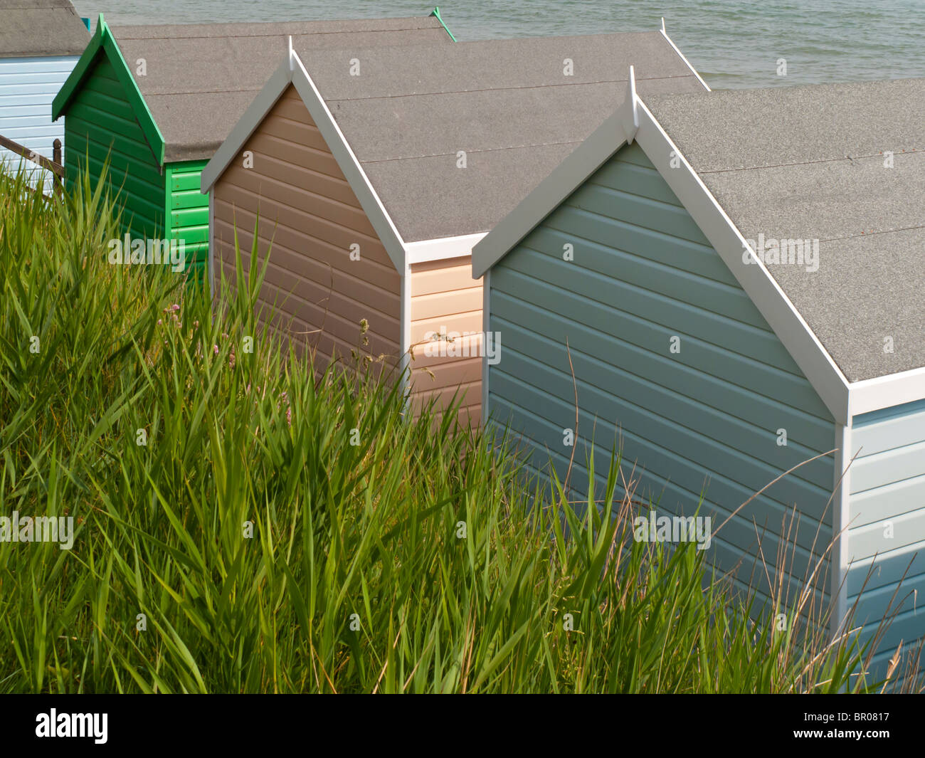 Pastell farbigen hölzernen Umkleidekabinen am Meer in Milford am Meer in Hampshire, England UK mit grünen Rasen im Vordergrund Stockfoto