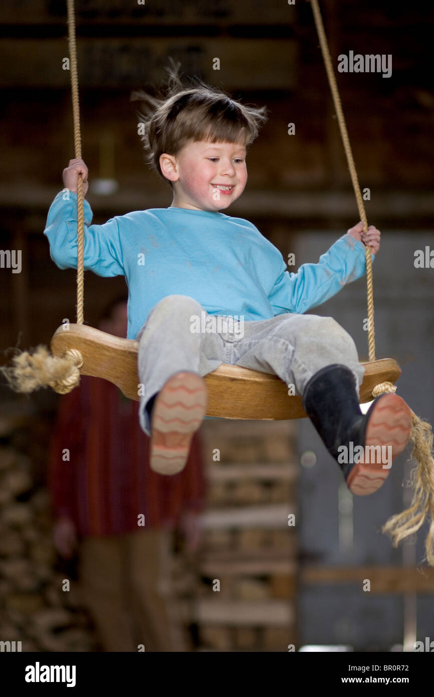 Ein Kind spielt auf einer Schaukel in einer alten Scheune in Yarmouth, Maine. Stockfoto