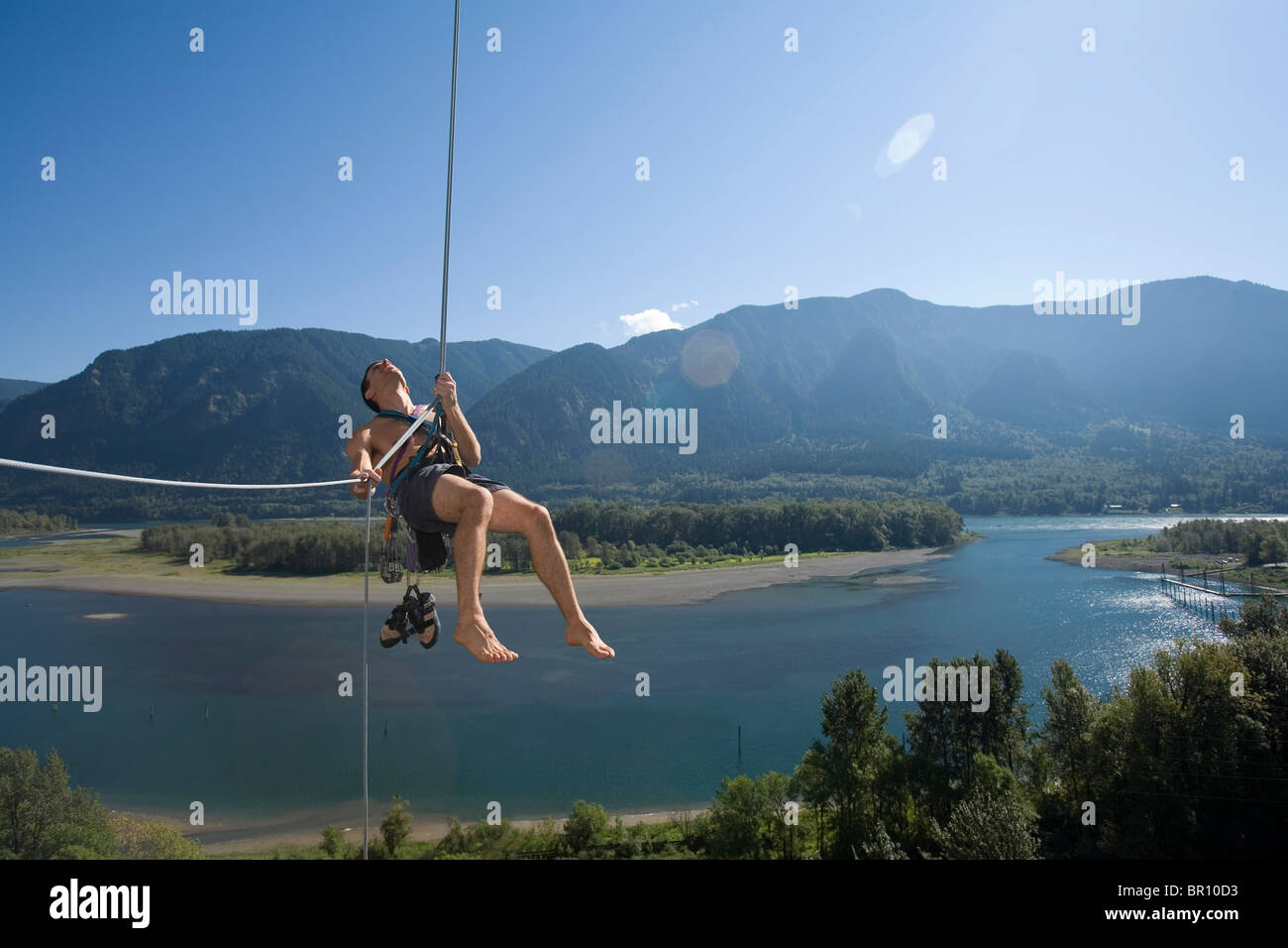 Junge Frau belays Kletterer hoch über den Columbia River. Stockfoto