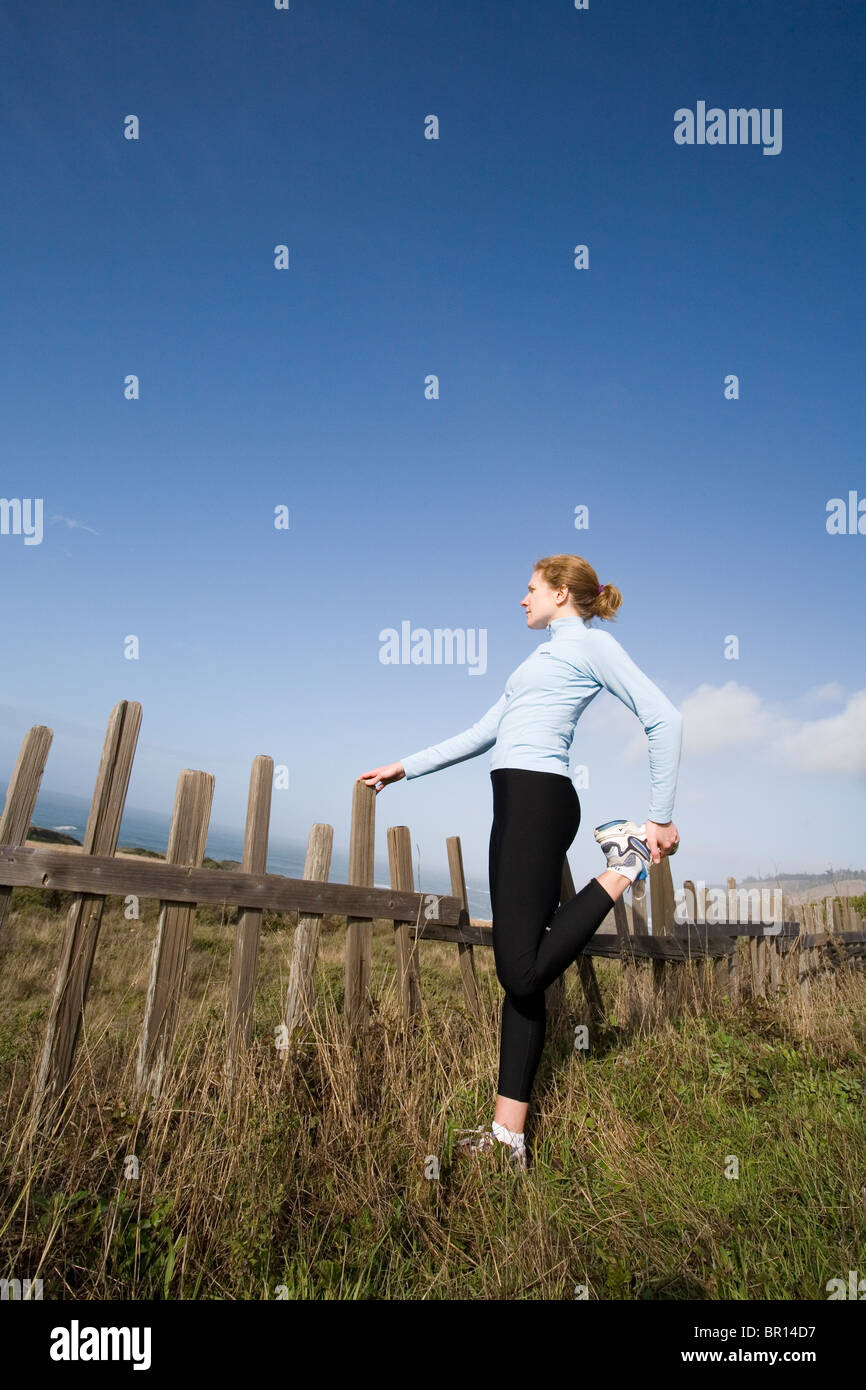 Eine junge Frau erstreckt sich vor Lauf entlang der Küste von Nord-Kalifornien in der Nähe von Mendocino, Kalifornien. Stockfoto