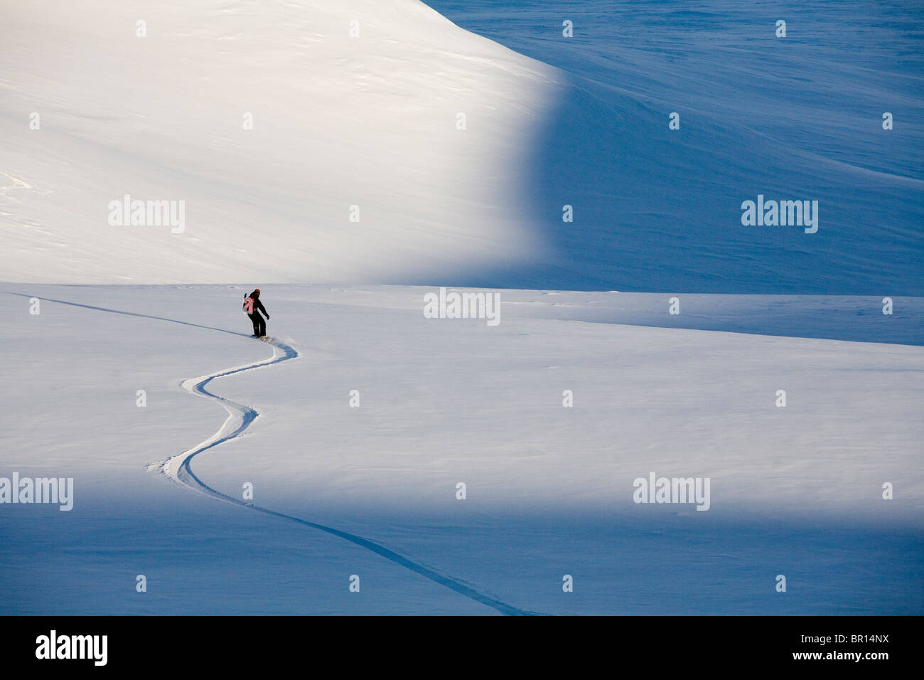 Mann Snowboards sanften Abhang am späten Nachmittag. Stockfoto