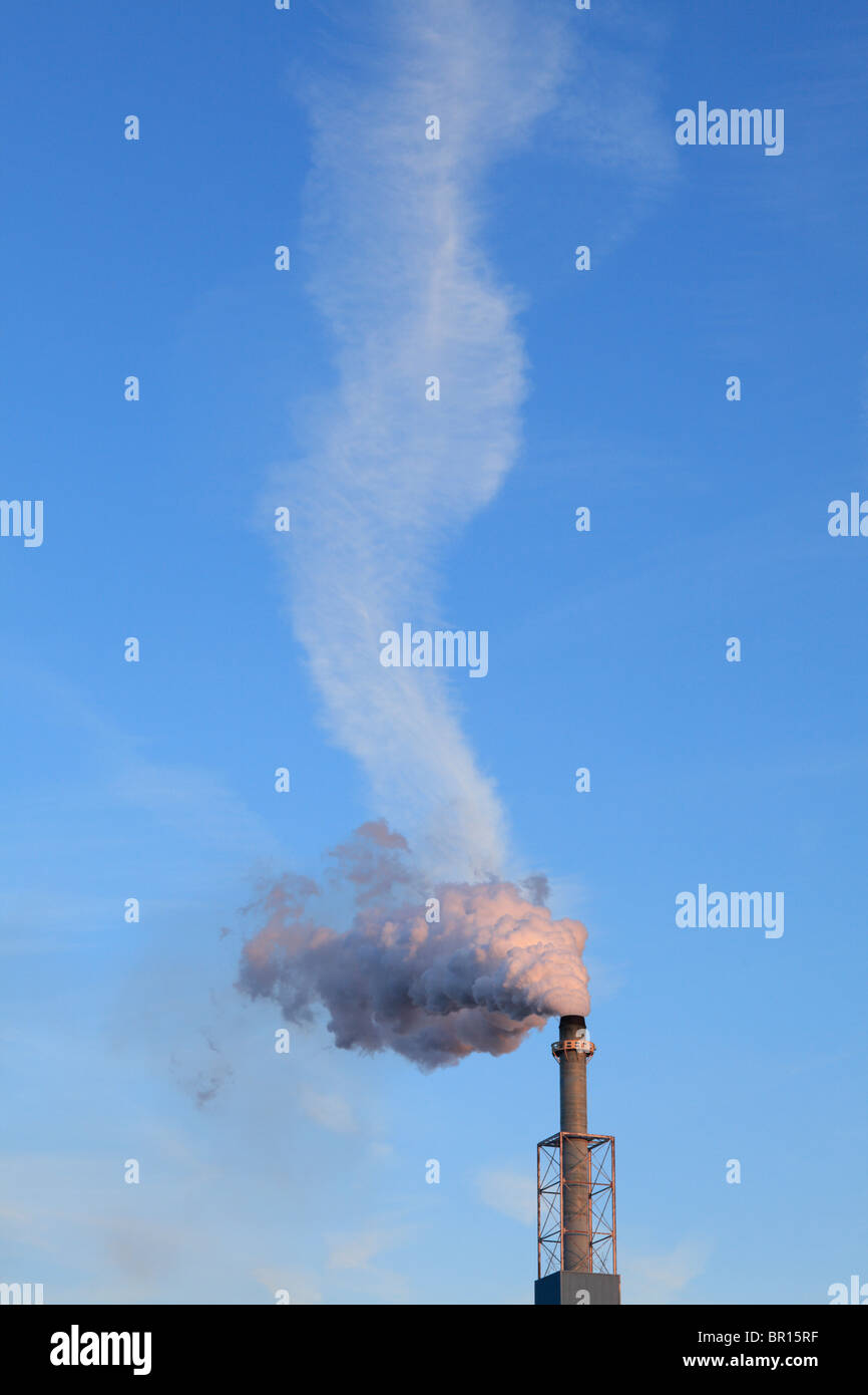 Rauch aus einem Schornstein und einer Hintergrundwolke. Stockfoto
