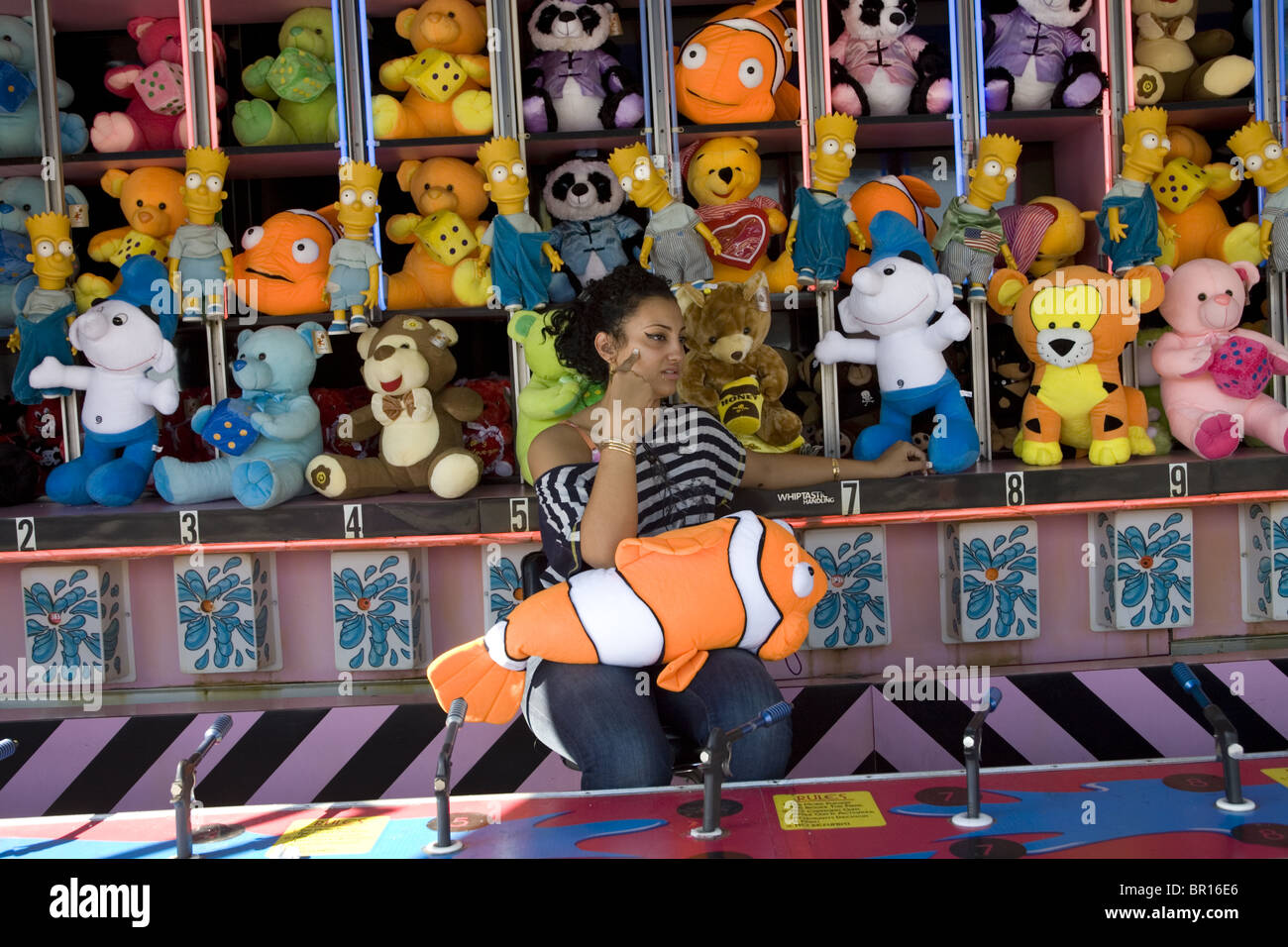 Arcade-Arbeiter wartet darauf, dass Menschen zu intensivieren und versuchen ihr Glück an einem der vielen Spiele im Vergnügungspark auf Coney Island Stockfoto