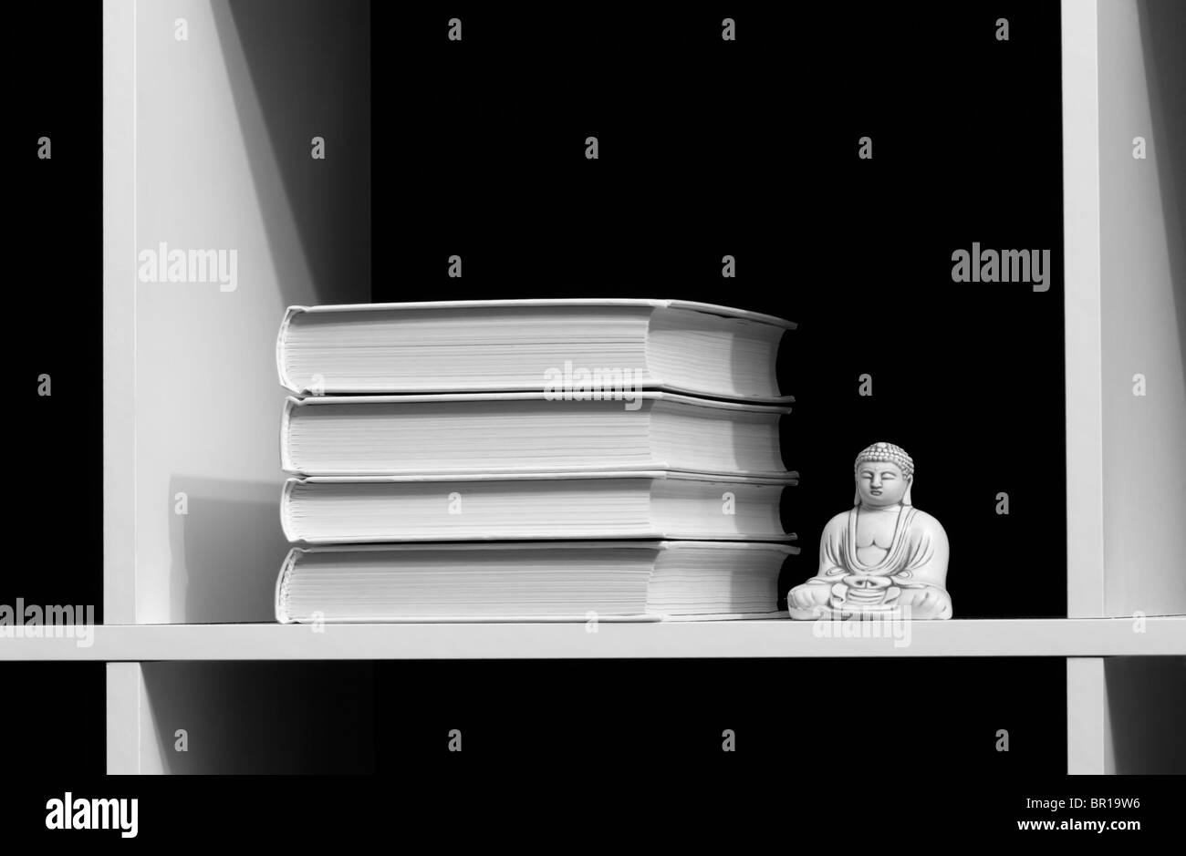 Bücher auf einem Regal und Buddha über dunkel. WB-Bild Stockfoto