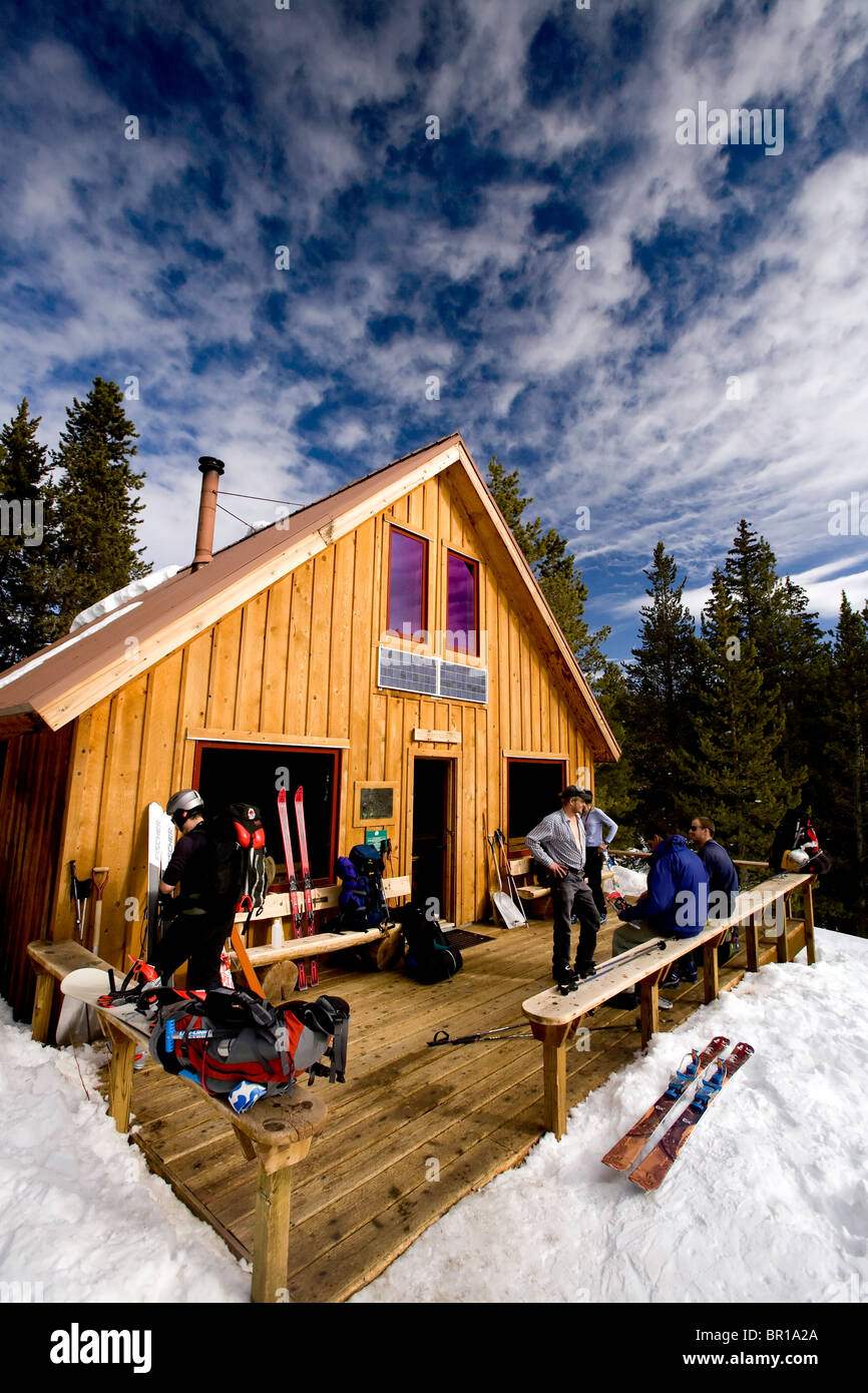 Blick auf eine Hütte an einem Wintertag. Gruppe von Personen auf der Veranda, die Vorbereitung für einen Tag voller Backcountry Telemarken. Stockfoto
