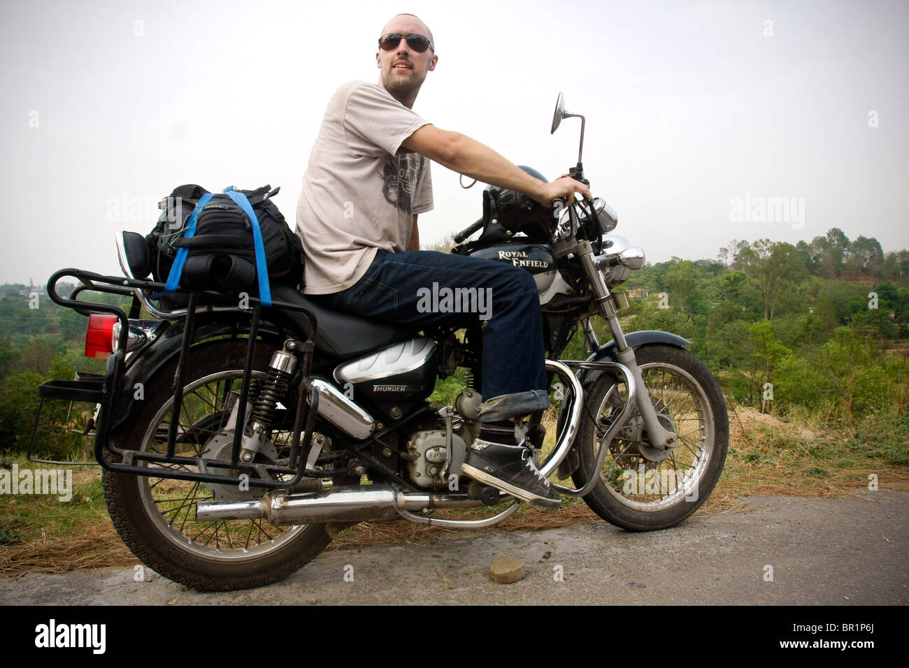 Ein Mann sitzt auf einem Royal Enfield 'Bullet' Motorrad während einer Motorradtour im Himalaya in Himachal Pradesh in Indien Stockfoto