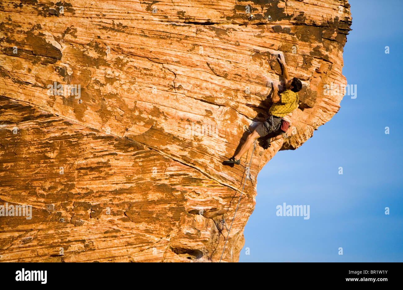 Ein Mann klettert eine Arete auf einem Sandstein-Felsen in der Wüste. Stockfoto