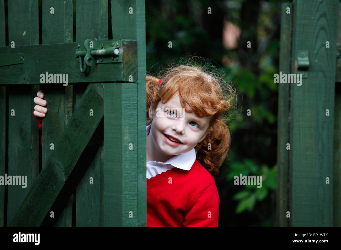 Kleines Mädchen, 4 Jahre, tragen ihre Schuluniform in einem Garten. Stockfoto