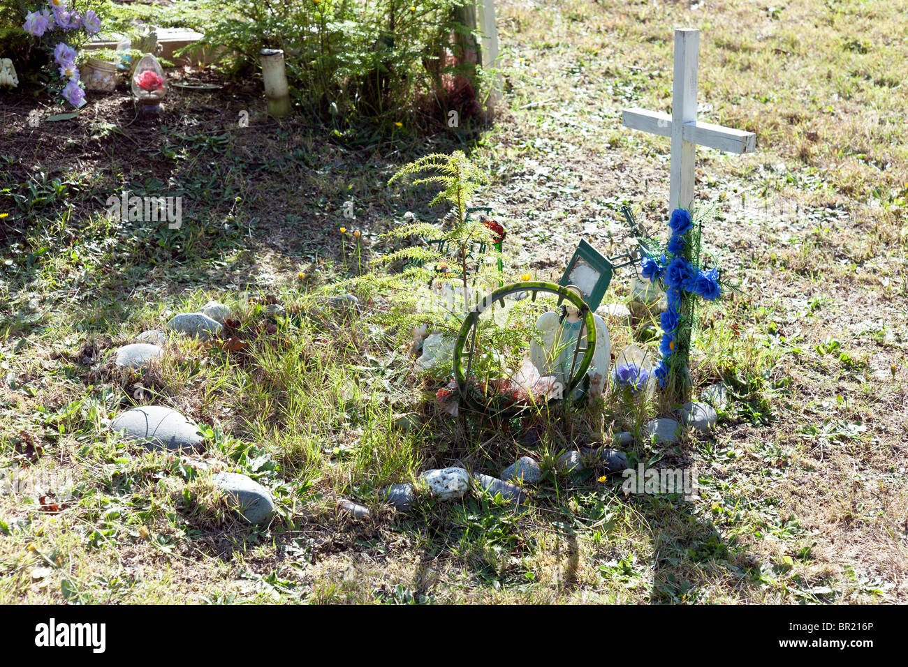 überwucherte Grab des jungen Makah Inderin mit Figuren Plastikblumen & einfache Holzkreuz in Makah Friedhof markiert Stockfoto