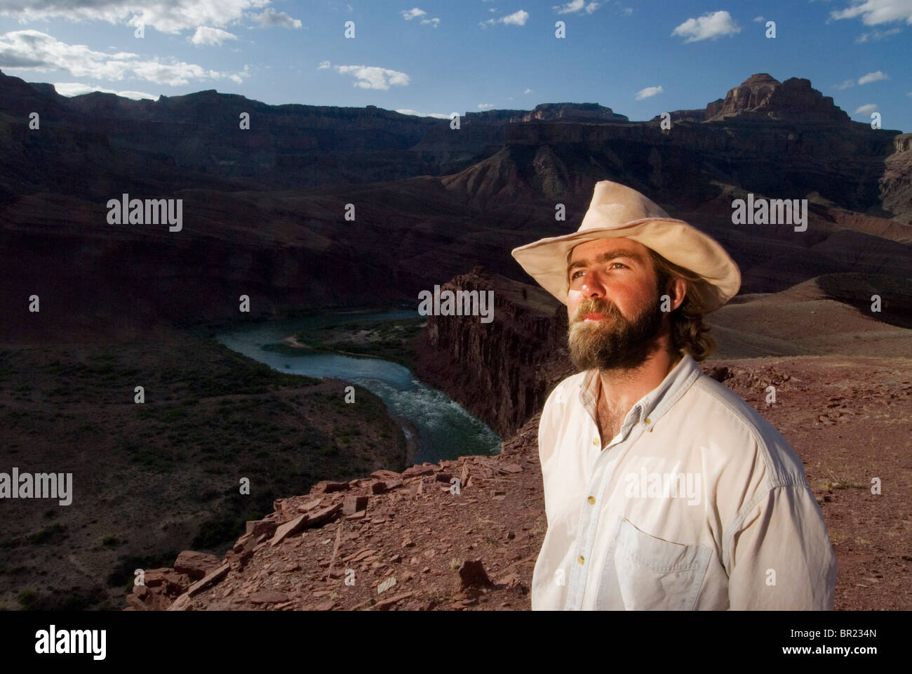 Ein Mann mittleren Alters in einem Cowboy-Hut blickt über den Colorado River im Grand Canyon National Par, Arizona. Stockfoto