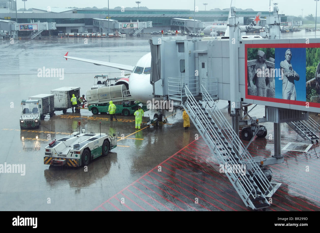 Boden-Crew Entladen eines Airbus A320 von Air Asia am Changi Airport in Singapur an einem regnerischen Tag. Stockfoto