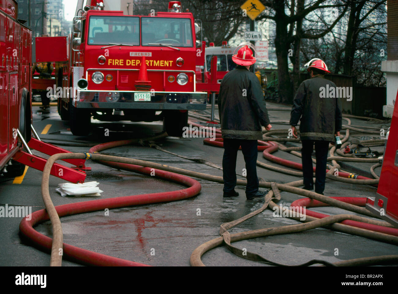Feuerwehr / Feuerwehrleute stehen inmitten von Feuerwehrschläuchen und LKW, Vancouver, Britisch-Kolumbien, Kanada Stockfoto