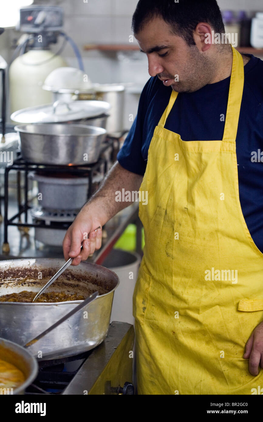 Ein Koch im berühmten Restaurant Azura rührt einen Topf mit Soße in der Mahane Yehuda Markt, Jerusalem, Israel Stockfoto