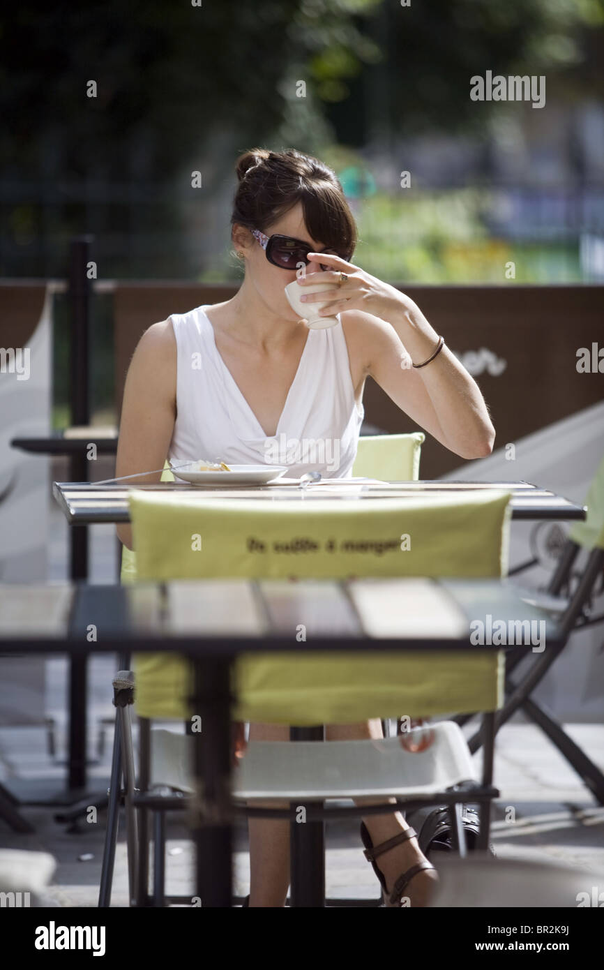 Eine junge Frau trinkt Kaffee vor einem Café auf dem Markt auf Rue Mouffetard, Paris Stockfoto