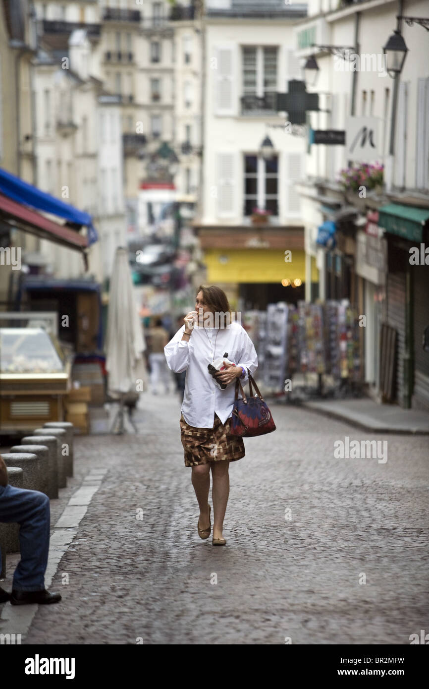 Eine Frau isst frisches Brot, wie sie den Markt in der Rue Mouffetard, einen berühmten Lebensmittelmarkt in Paris geht Stockfoto