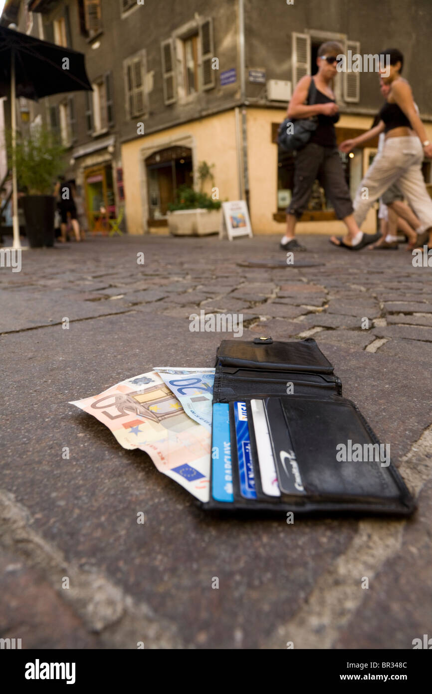 Verlorene Geldbörse mit Euro / Europäische Banknoten und zeigt UK Bank- und Kreditkarten, liegend auf einer gepflasterten Straße in Frankreich. Stockfoto