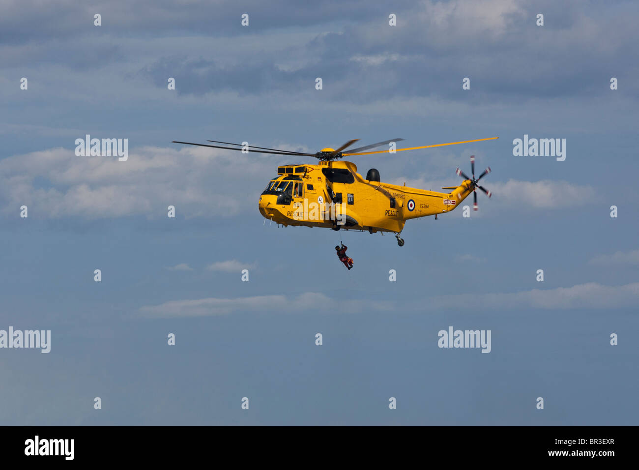 RAF-Meerkönigs Rettungshubschrauber, senkt eine Winchman an einem wartenden RNLI inshore Rettungsboot. Stockfoto