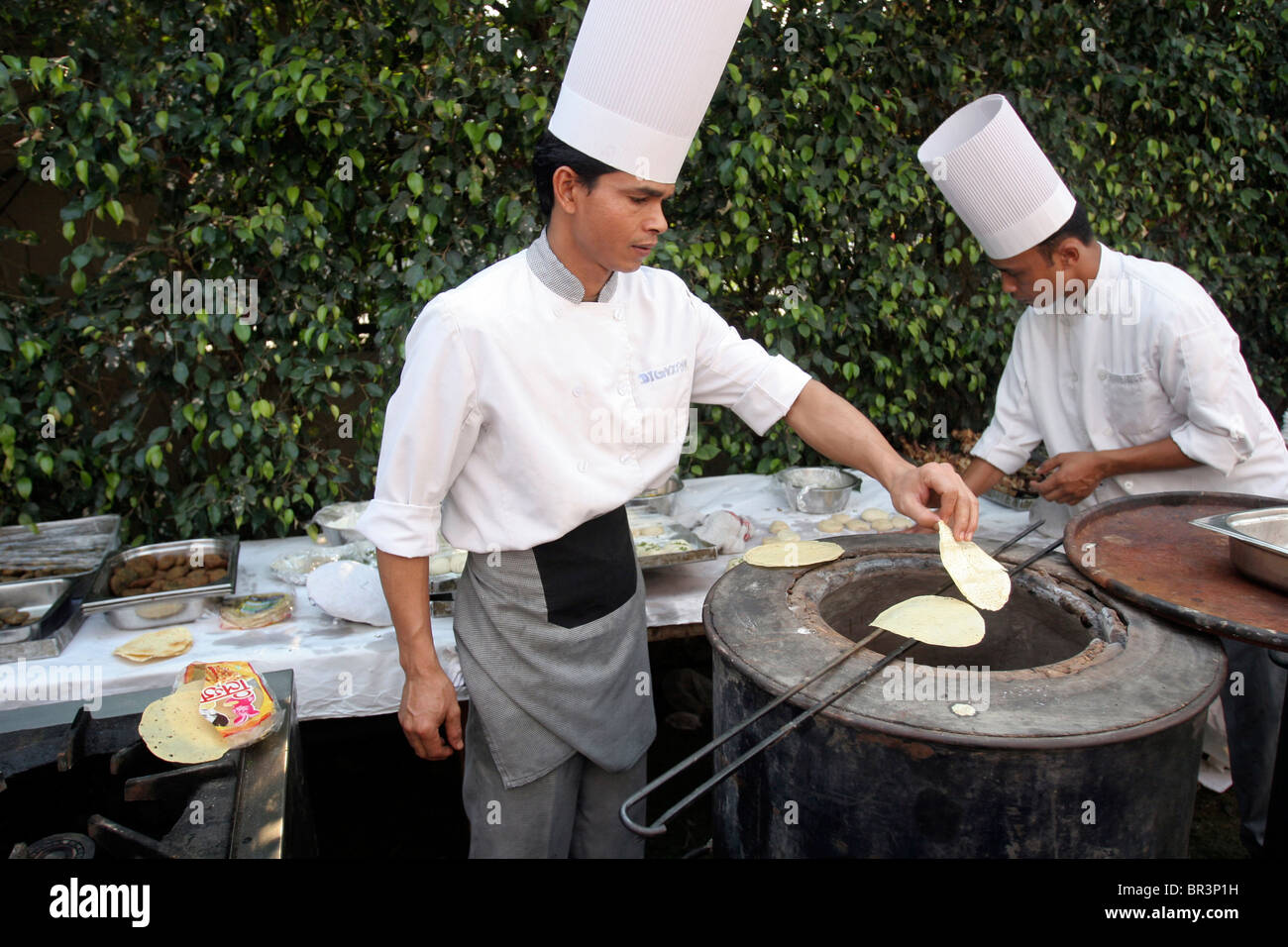 Zwei Köche bereiten Chapati-Brot in einer traditionellen tandoori Ofen während einer Hochzeit in Neu-Delhi in Indien. Stockfoto