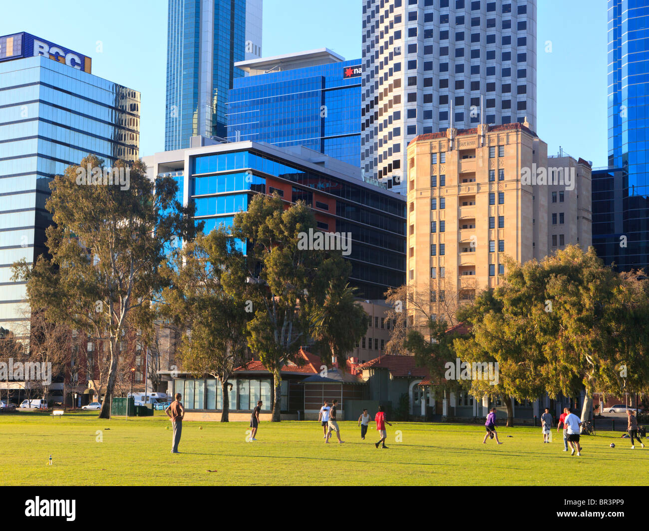 Büroangestellte, die Fußball spielen auf ihr Mittagessen in einem Park neben der Stadt zu brechen. Stockfoto