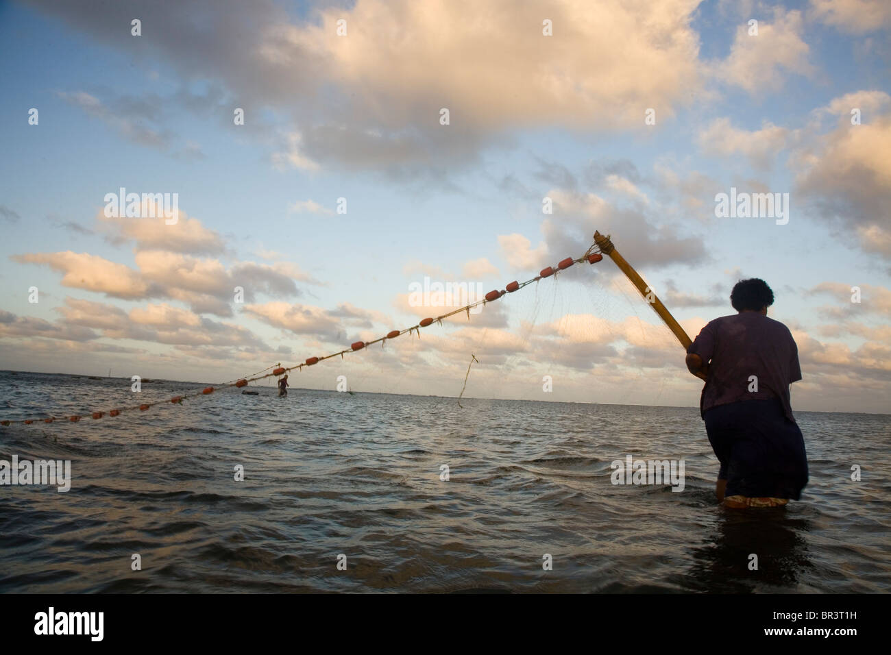 Ein Mann hält die Enden eines Netzes, während eine Frau keine Gefangenen Fische sammelt. Stockfoto