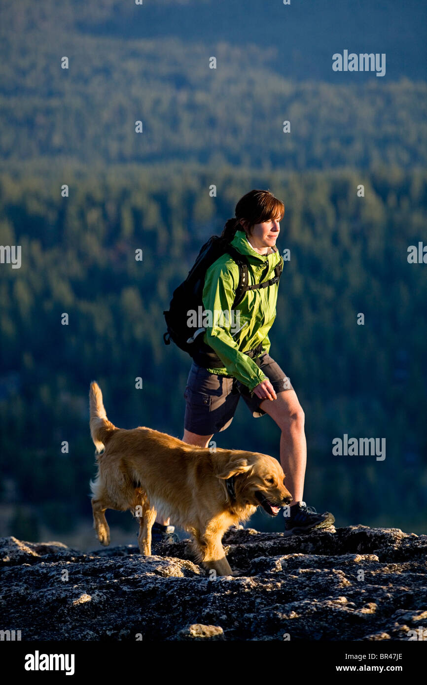 Frau mit ihrem Hund hoch über einem blauen Bergsee wandern. Stockfoto