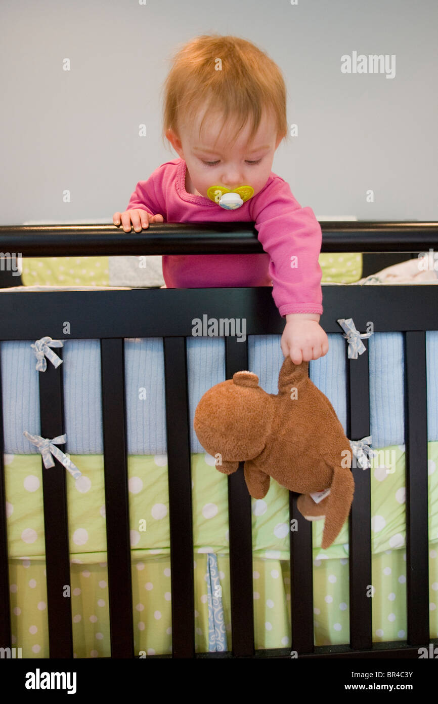 Ein Baby baumelt ihr Stofftier außerhalb ihrer Krippe, Newry, Maine. Stockfoto