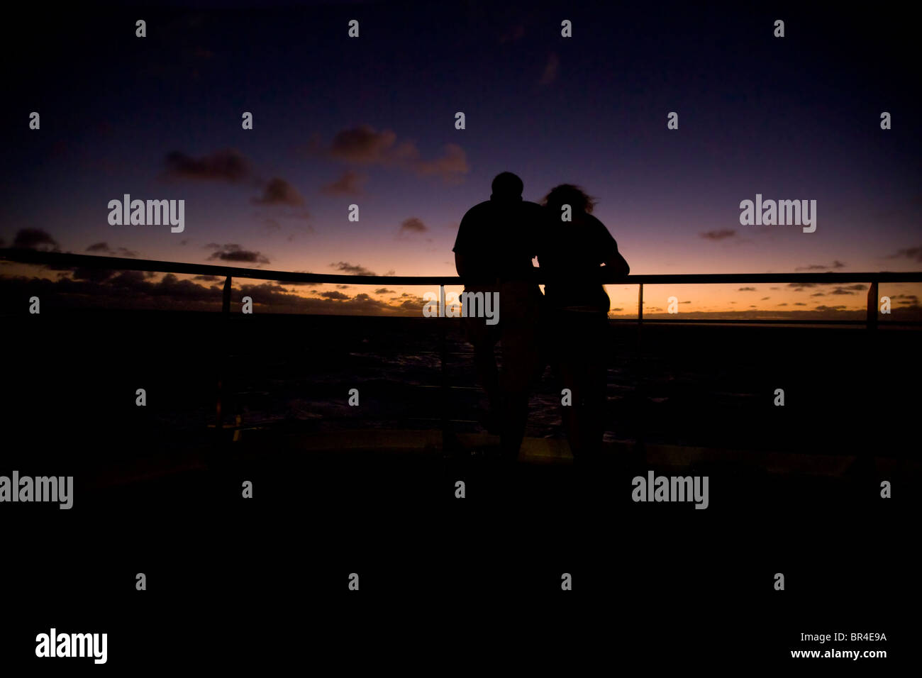 Silhouette von zwei jungen Erwachsenen Mann und Frau auf dem Deck eines Kreuzfahrtschiffes Schiff bei Sonnenuntergang am Atlantischen Ozean. Stockfoto
