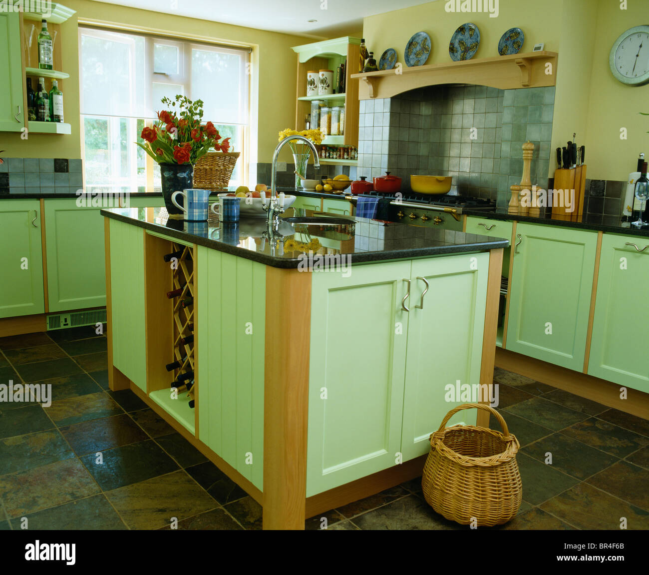 Korb am Boden neben Insel Einheit mit Granit-Arbeitsplatte in Landhaus-Küche  mit hellen grünen montierten Einheiten Stockfotografie - Alamy