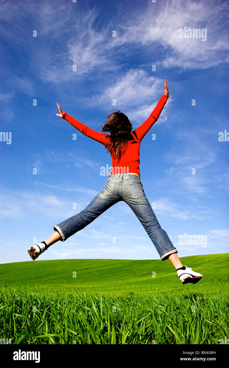 Frau macht einen großen Sprung auf einer schönen grünen Wiese Stockfoto