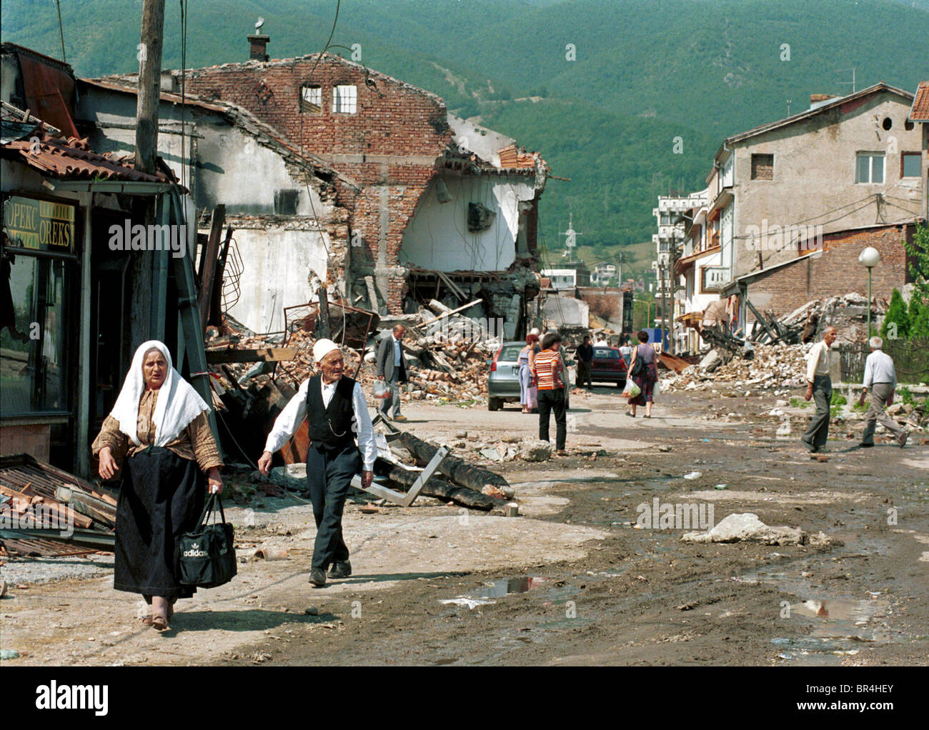 Die Menschen gehen die Straße vorbei an der Zerstörung in Peja, Kosovo  Stockfotografie - Alamy