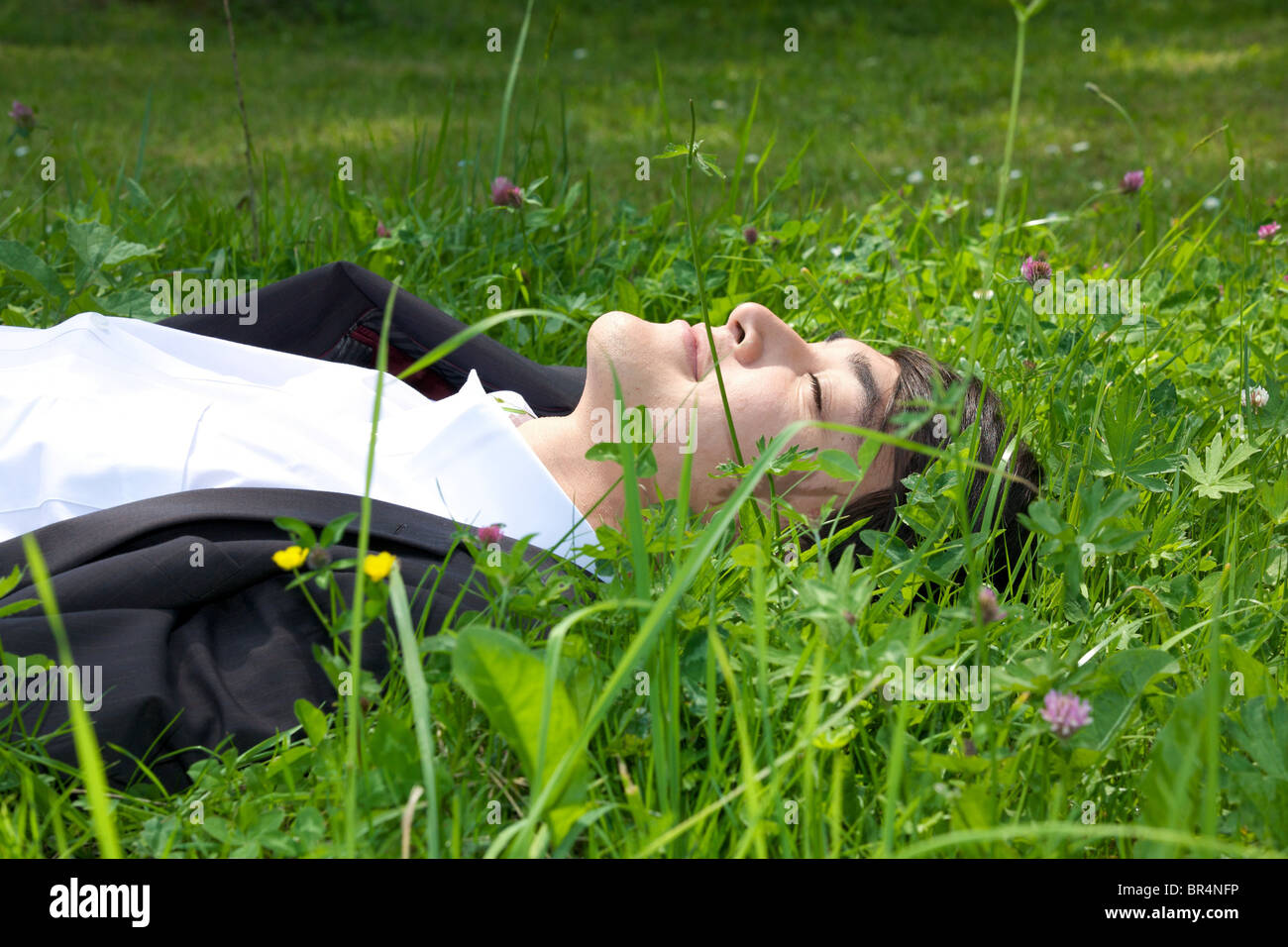 Junger Geschäftsmann in der Wiese liegend Stockfoto