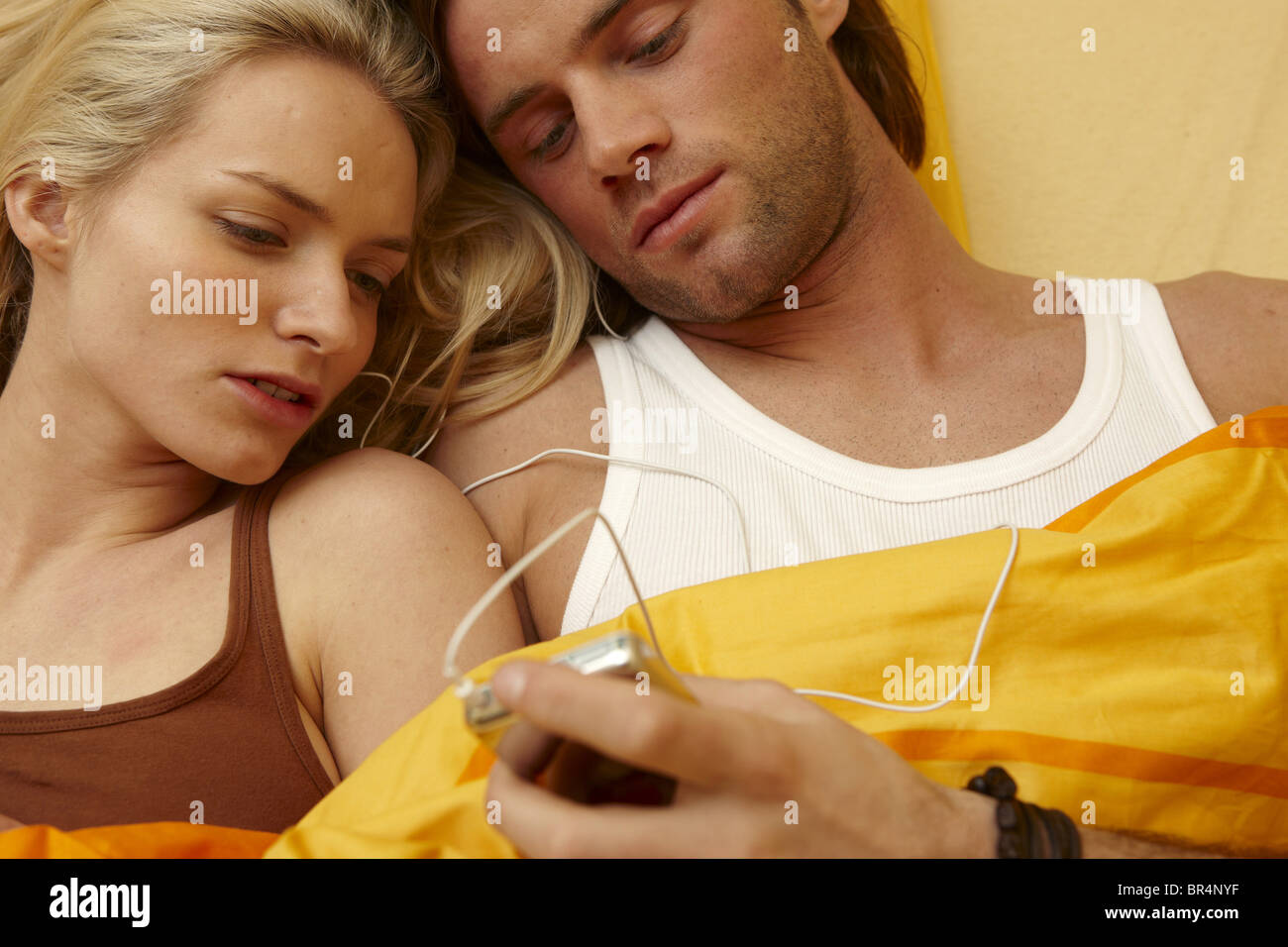 Junges Paar im Bett mit MP3-player Stockfoto