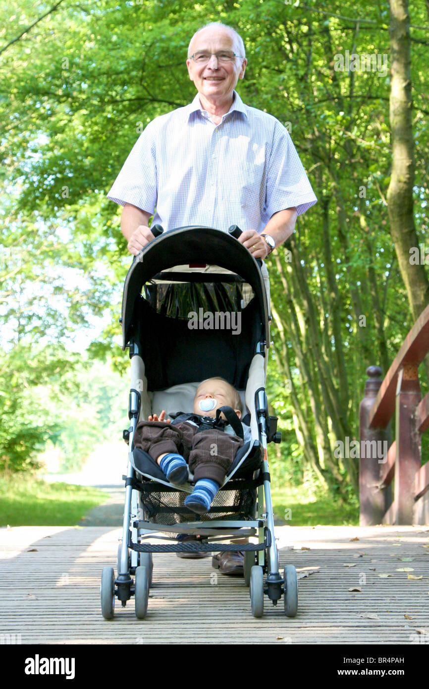 Großvater gehen für einen Spaziergang-Enkel im Kinderwagen Stockfoto