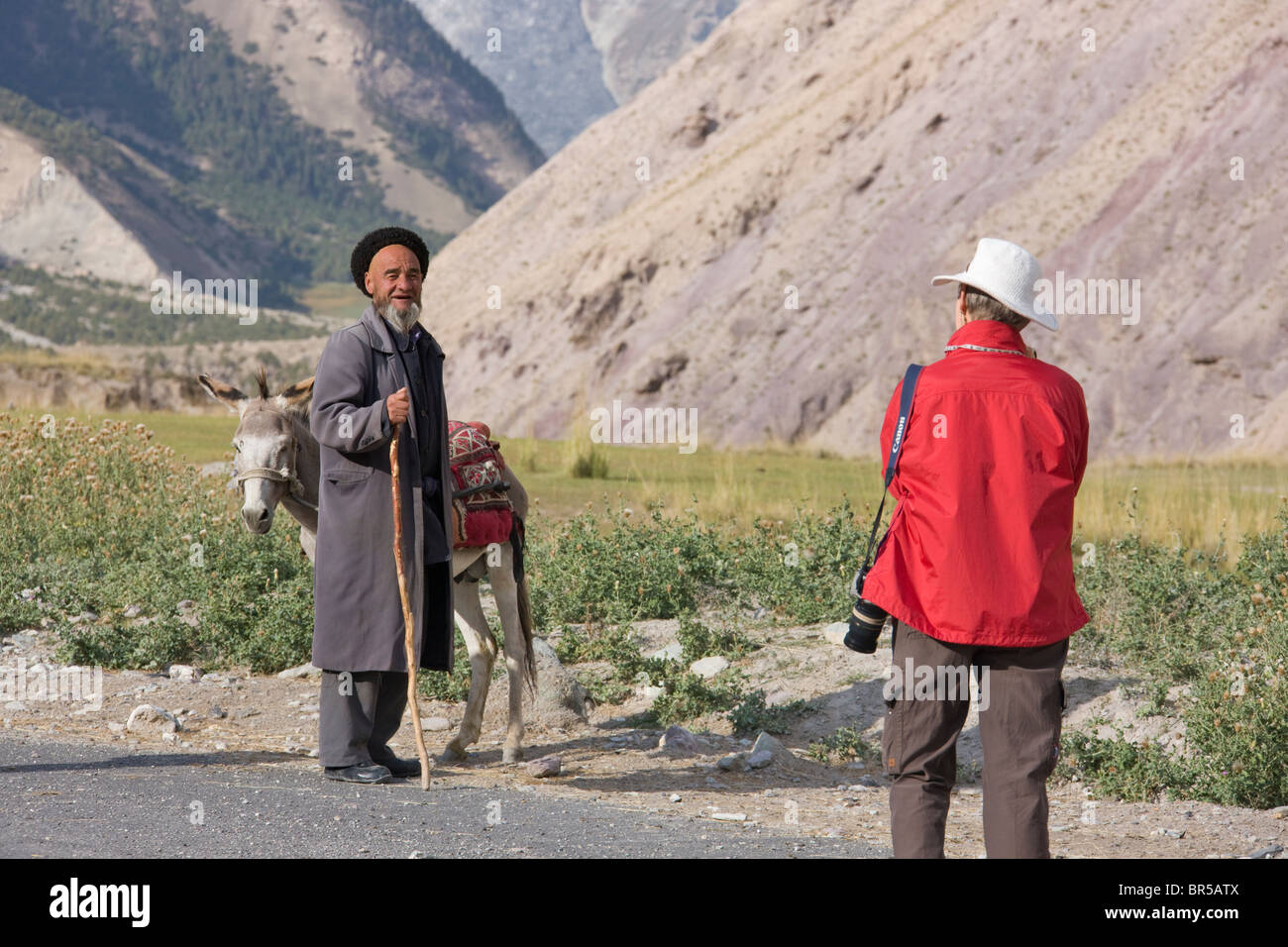 Westliche Touristen fotografieren Taijk Mann mit Esel, Aoyitage Tal, Pamir Plateau, Xinjiang, China Stockfoto