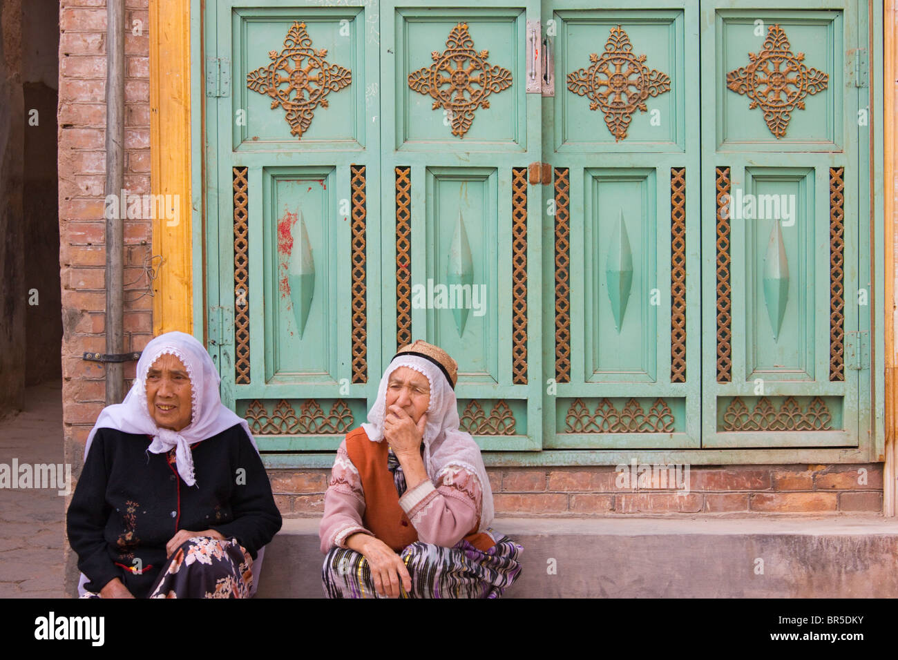 Uigurische Frau durch traditionelle Tür, Kashgar, Xinjiang, China Stockfoto