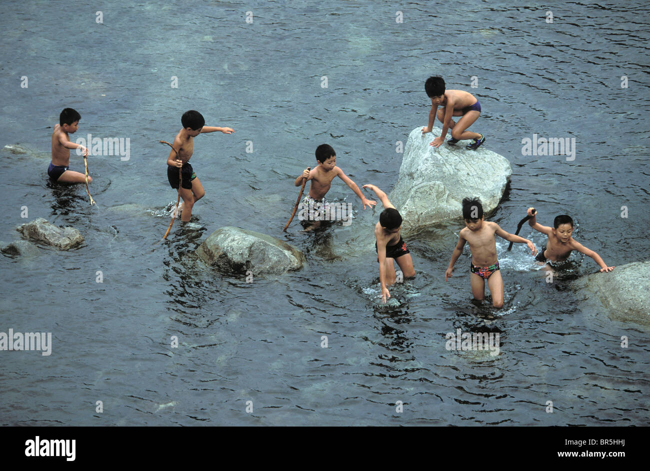 Japans Jungen spielen in einem stream Stockfoto