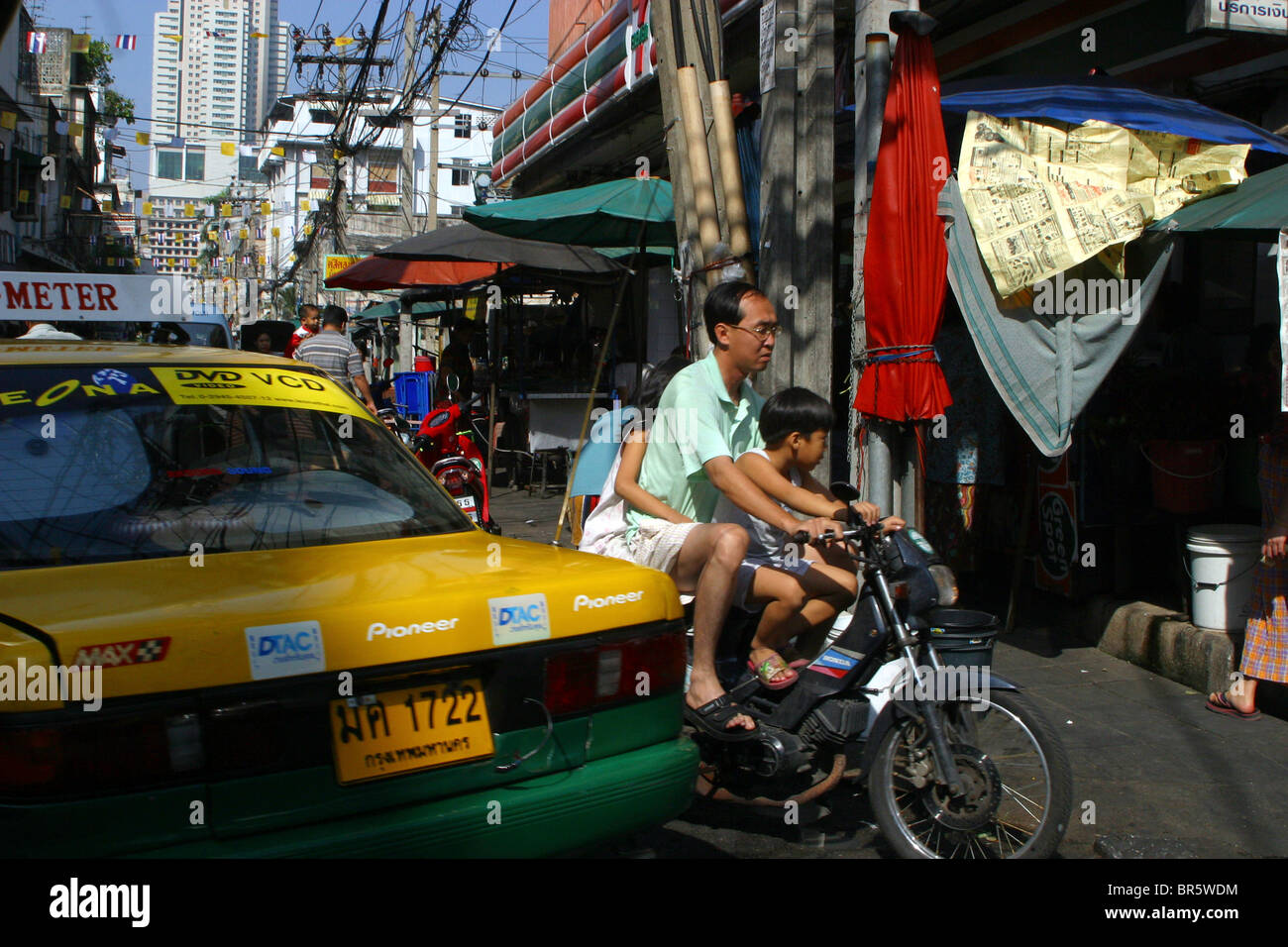 Eine Thai-Familie von 3 Reisen auf einem Roller-Pass ein Taxi auf den Straßen von Bangkok, Thailand Stockfoto