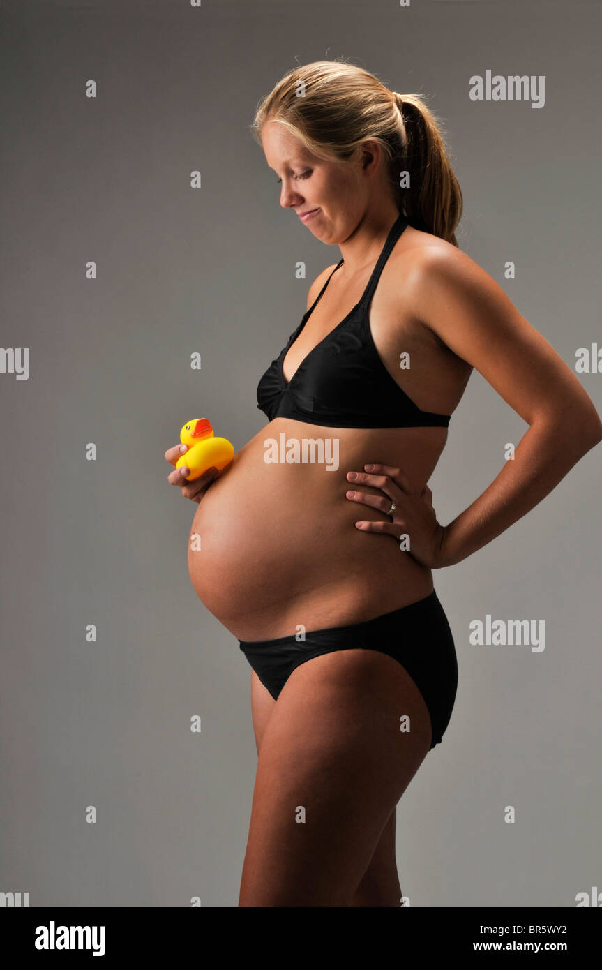 Schwangere Frau mit Requisiten und schwarzen Badeanzug auf weißem Hintergrund. Stockfoto