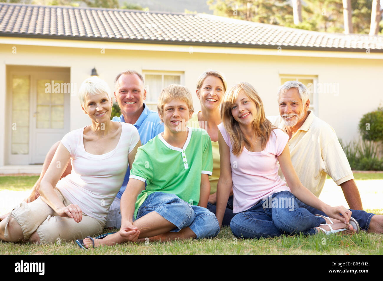 Erweiterte Familie sitzen außen Traumhaus Stockfoto