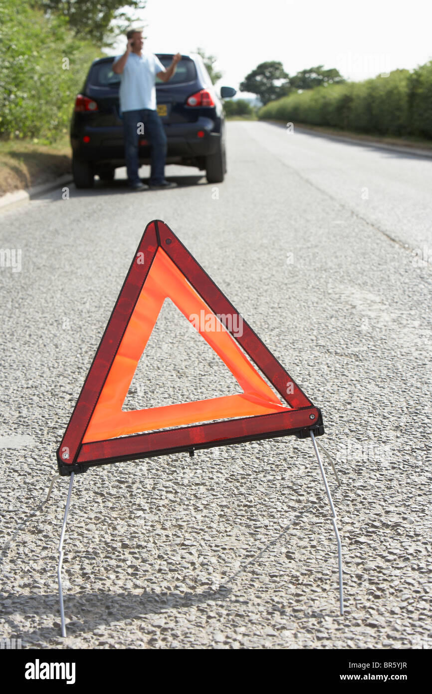 Fahrer, die Broken Down auf Landstraße mit Gefahr Warnzeichen im Vordergrund Stockfoto
