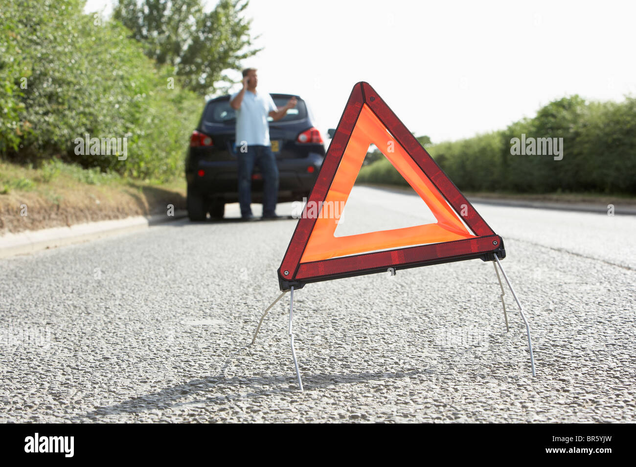 Fahrer, die Broken Down auf Landstraße mit Gefahr Warnzeichen im Vordergrund Stockfoto