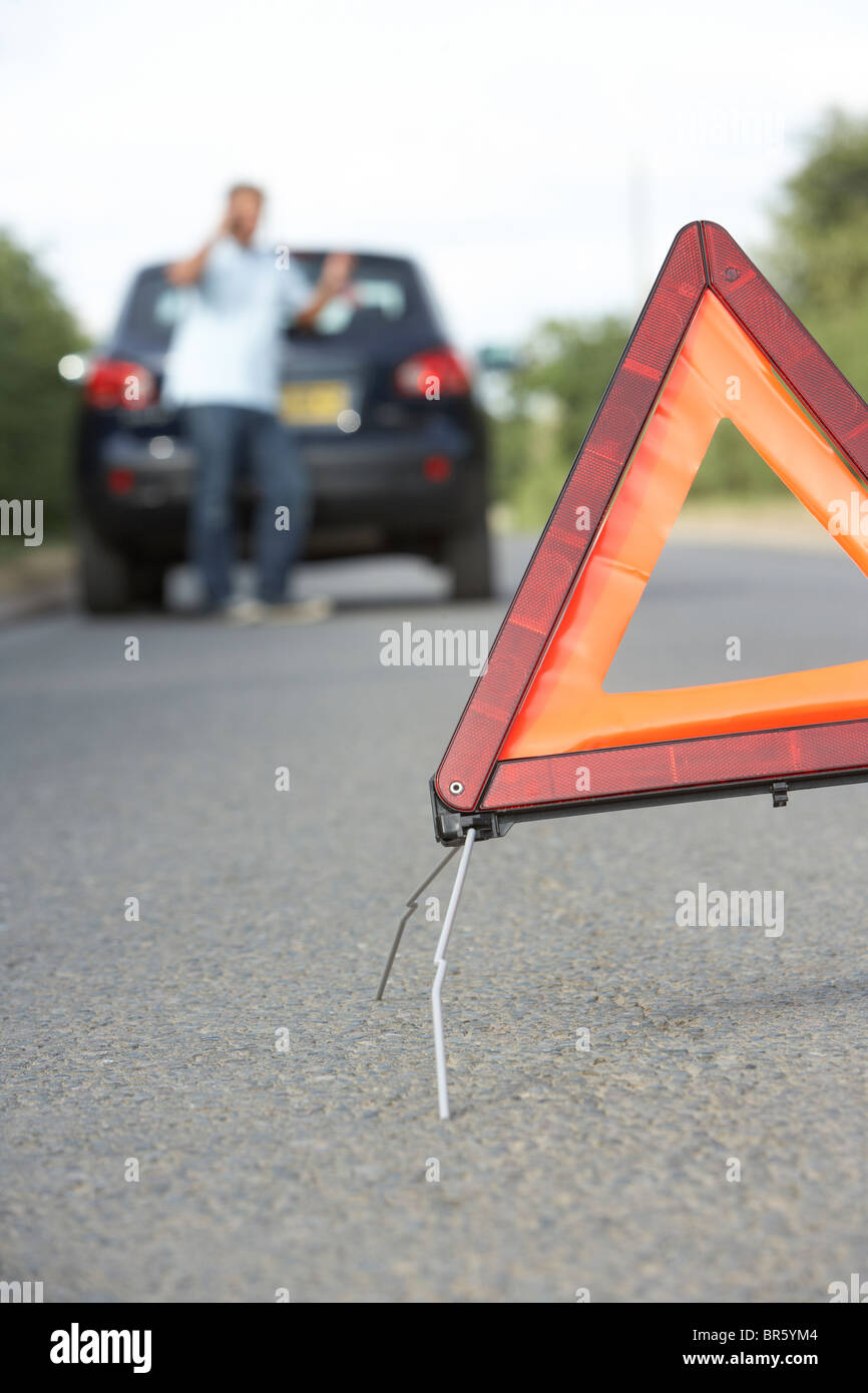 Fahrer, die Broken Down auf Landstraße mit Gefahr Warnzeichen im Vordergrund Stockfoto