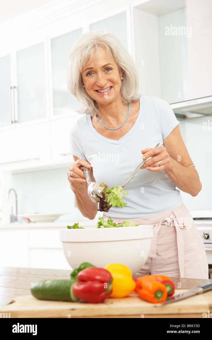 Ältere Frau bereitet Salat In modernen Küche Stockfoto
