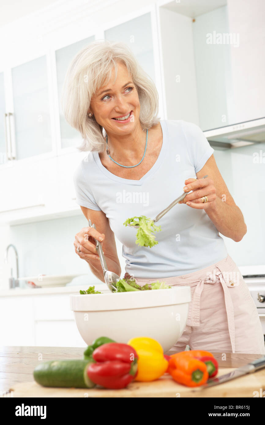 Ältere Frau bereitet Salat In modernen Küche Stockfoto